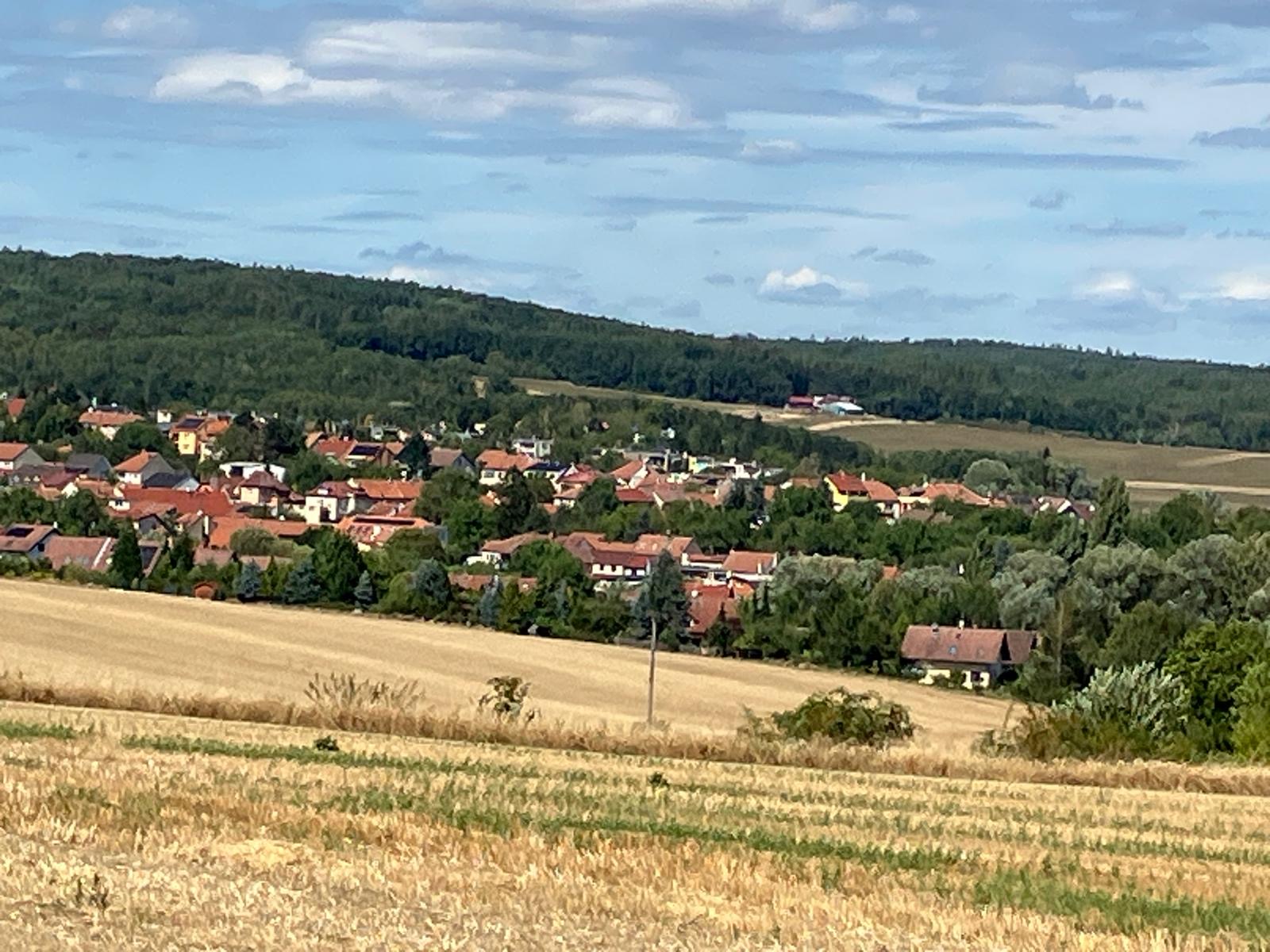 Pohled na Žebětín obklopený lesy a loukami